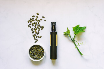 Kürbiskernöl in einer braunen Glas Flasche und geröstete Kürbiskerne in einer Schüssel auf...