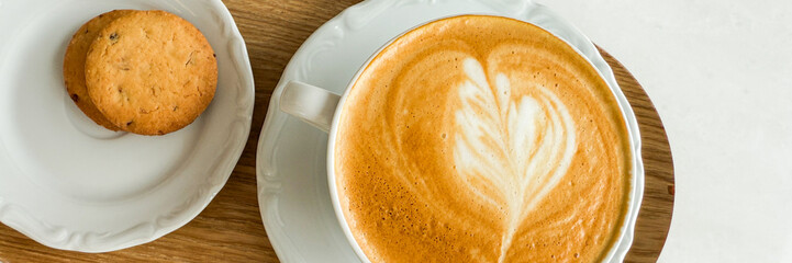 Creamy latte with delicate heart art whispers cozy autumn mornings, Hygge spirit, paired with anise-flavored biscotti delight