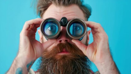 A man with a beard and glasses looking through binoculars. He has tattoos on his arm - Powered by Adobe