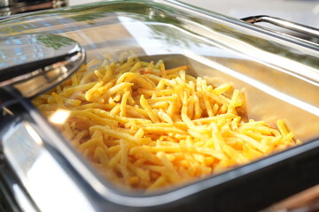 Crispy golden French fries served in a stainless steel buffet tray at catering event, delicious fast food snack option for party, restaurant, hotel breakfast, lunch or dinner service, fresh and hot.