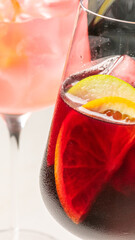 A vibrant dance of citrus slices in crimson sangria glass, evoking Mediterranean summer and La Tomatina festival zest