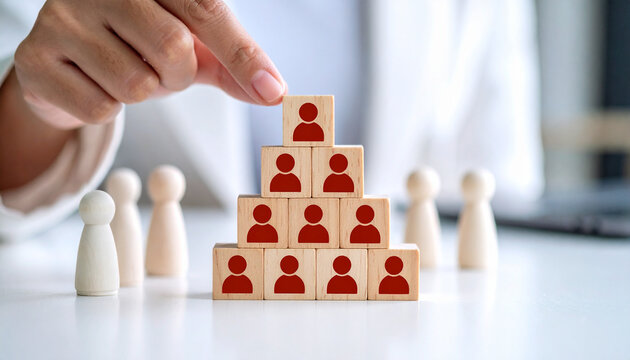 A hand arranging blocks to represent a hierarchy in an office. The image showcases the building of team structure and organization in the workplace