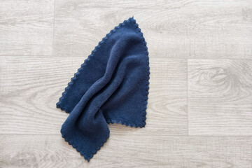 Blue cleaning cloth with wavy edge. On white wooden background.