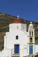 Fototapeta premium church with a whitewashed facade and red dome surrounded by a small cemetery with white tombstones and crosses in Olympos village, Karpathos island, Dodecanese, Greece