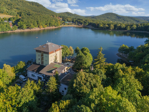 Aerial view of the vibrant Po&Auml;&Atilde;&ordm;vadlo Lake reflecting the azure sky, embraced by lush green forests and a prominent tower, Pocuvadlo lake, Banskobystrick&Atilde;&frac12; kraj, Slovakia.