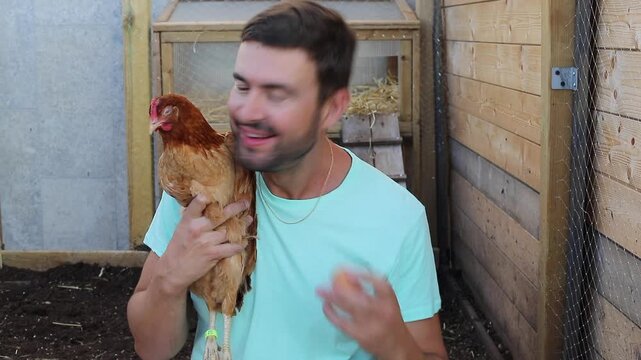 Man holding a brown chicken and one egg 