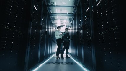 Timelapse: It Specialists and Engineers Walk and Work Inside a Data Center Server Room, Checking Equipment and Monitoring Racks Filled With Servers and Network Hardware for Artificial Intelligence HUB - Powered by Adobe