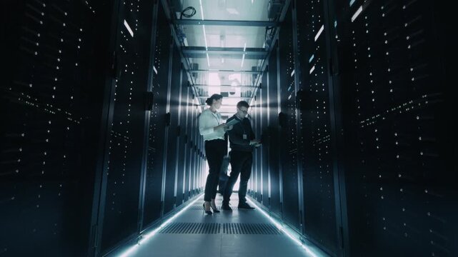 Timelapse: It Specialists and Engineers Walk and Work Inside a Data Center Server Room, Checking Equipment and Monitoring Racks Filled With Servers and Network Hardware for Artificial Intelligence HUB - Powered by Adobe