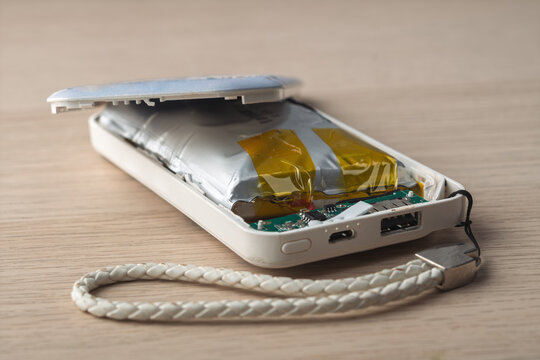 Swollen lithium battery bursting open damaged power bank case illustrates danger of overheating, explosion risk and electronic failure.