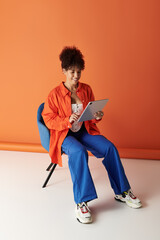 Curly woman engages with her device in a vibrant studio space