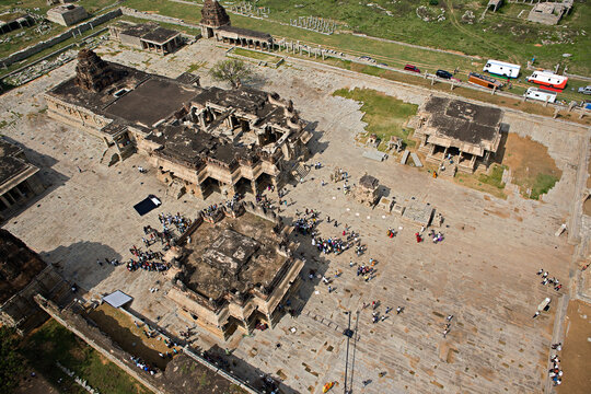 Aerial view of ancient ruins, weathered stone structures, and gatherings of people amidst the historical landscape, Hampi, Karnataka, India.