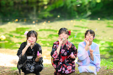 浴衣を着た日本人の小学生の女の子がシャボン玉で遊ぶ夏の風景