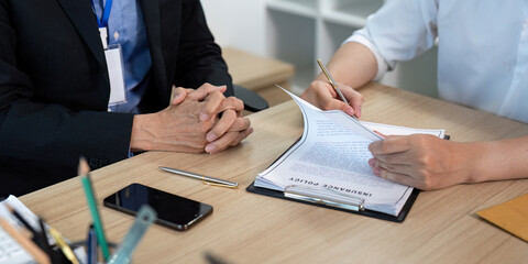 Signing Insurance Policy. Client reviewing and signing policy document in a business environment.