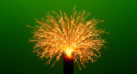 A vibrant sparkler emitting golden sparks against a green background, creating a festive atmosphere.