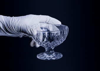 A Close-up and Detailed View of a Human Hand Delicately Holding a Single, Vibrant Blue Pill, with the Background Featuring a Deliberately Blurred Glass Pharmaceutical Bottle Filled 
