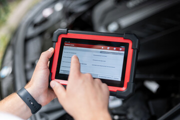 Person holding a car diagnostic scanner inside vehicle cabin, checking electronic systems and engine performance. Automotive technology and repair concept.