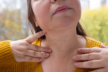 Woman touching hand collar bones and décolletage, examines wrinkles on skin, freckles and moles,...