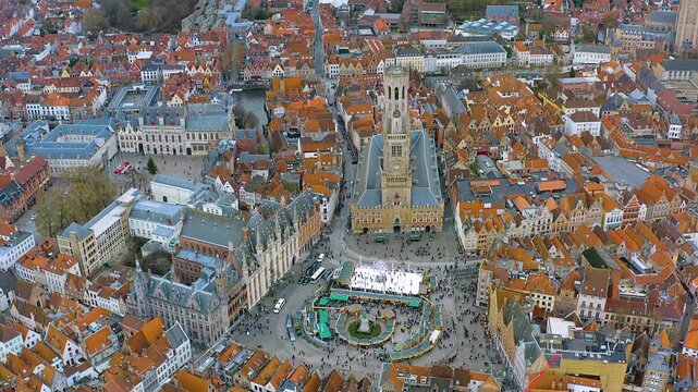 4K drone view of Bruges&rsquo; Markt and the Belfry, with a lively Christmas market and ice rink set among red - tiled medieval rooftops in Belgium&rsquo;s UNESCO old town.