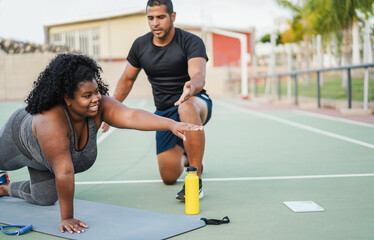 Curvy african american girl and her personal trainer doing sport workout session outdoor - Sport, diet and healthy lifestyle concept - Main focus on girl face