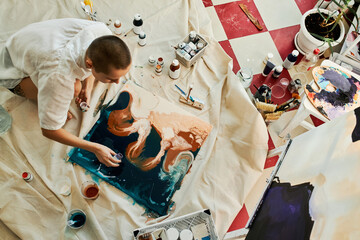 Horizontal from above view shot of professional artist creating fluid art picture adding some...