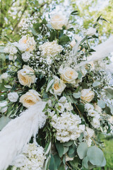 Elegant floral wedding arrangement with white roses, eucalyptus leaves, and gypsophila in natural outdoor light.