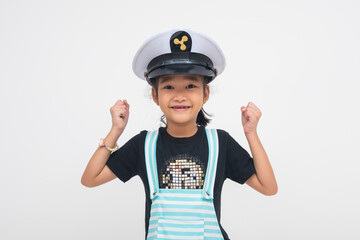 An elated young Asian girl beaming with delight, fist raised triumphantly, wearing a pilot cap and expressing ecstatic excitement and cheerfulness. Isolated on a white background.