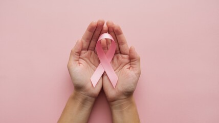 Female hands holding pink ribbon as a symbol of breast cancer awareness