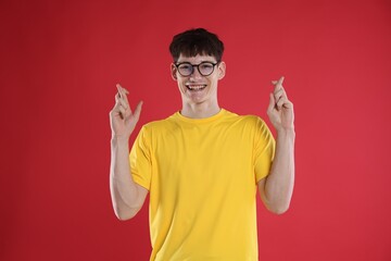 Naklejka premium Happy student crossing fingers for good exam result on red background