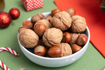 close-up of a bowl filled with hazelnuts and walnuts, resting on a festively adorned Christmas table