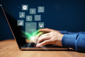 Hands typing on laptop with digital financial icons and data analytics displayed on screen in a modern workspace