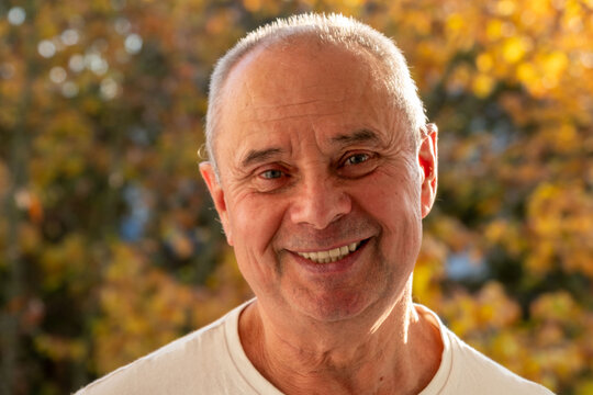 happy positive caucasian mature man 60-65 years old smiling on green natural background, good mood, age-related changes, mental human health