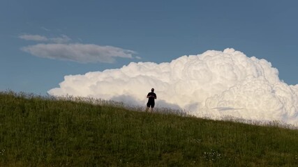Drone rise with camera rotation showing hiker on top of Monte Baldo as thunderstorm clouds emerge in parallax, Italian Alps, Italy