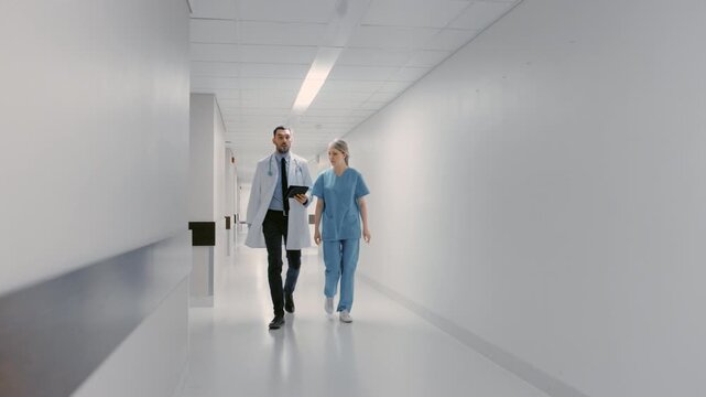 Medical Doctors and Nurses Walk Together Down a Hospital Hallway, Talking About Patient Diagnosis, Clinical Teamwork, Using Digital Tablet.