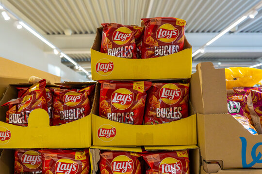 Lay&rsquo;s Bugles corn snack bags displayed in supermarket cardboard stand, red packaging with yellow Lay&rsquo;s logo, price label visible