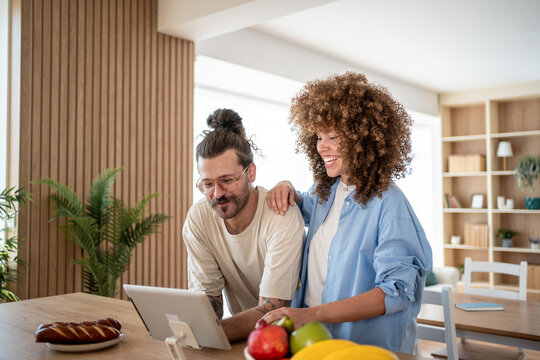 Happy couple browsing internet on tablet in kitchen with healthy food