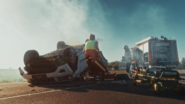 On the Car Crash Traffic Accident Scene: Paramedics and Firefighters Rescue Injured Victim Trapped in the Vehicle. Extricate Person Using Stretchers, Give First Aid and Transport Them to Hospital