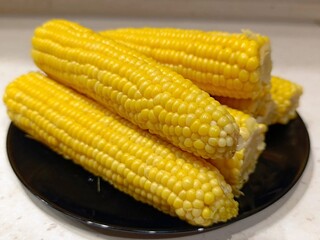 
Steamed sweet corn on a black plate.