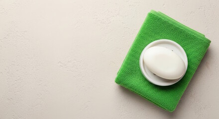 White soap bar placed on a round dish atop a vibrant green towel, showcasing a clean and minimalist bathroom aesthetic with soft textures and neutral tones