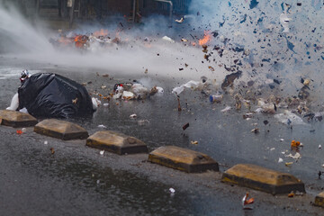 A man is laying on the ground next to a pile of trash. The trash is scattered all over the street.