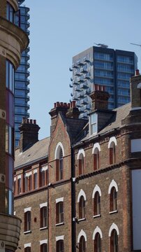 Buildings in central London, England with contrasting red and brown facades in daylight. Vertical