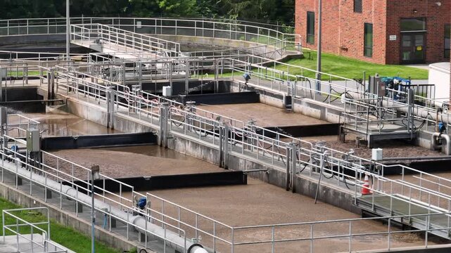 Sewage plant and wastewater treatment in America. Sunny day in suburb of town. Sedimentation tanks and pool filtering dirt. Aerial view.
