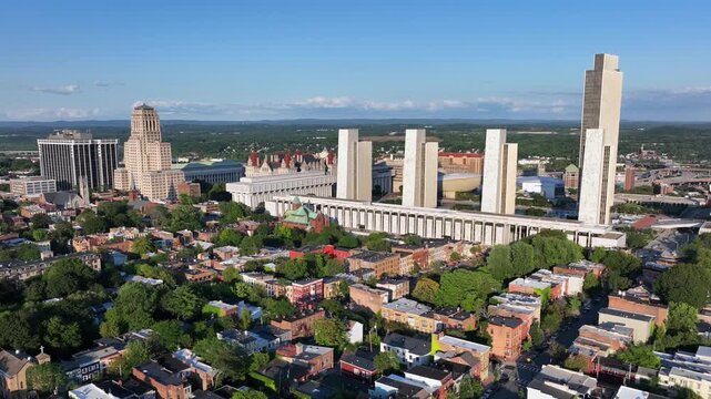 Albany, New York in summer. Aerial wide shot. Housing area with townhouses and row homes. Downtown with Alfred E. Smith State Office Building and Empire State plaza.