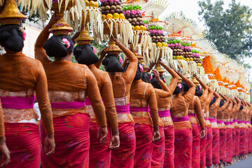 Procession of beautiful Balinese women in traditional costumes - sarong, carry offering on heads for Hindu ceremony. Arts festival, culture of Bali island and Indonesia people, Asian travel background