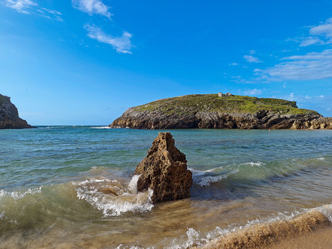 Waves crash on rocks at Cu&eacute; Beach by La Islona in Asturias