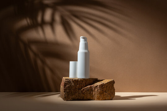 Cosmetic Bottle Mockup on Stone Podium with Palm Leaves Shadows in Minimal Natural Composition