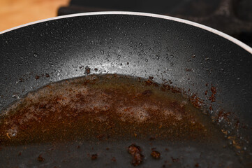 Burnt remains of used old oil in the pan, dirty pan
