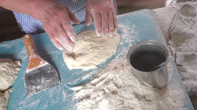 close up of hands of georgian elderly woman making bread dough and flatbreads