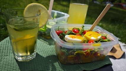 Close-up of fresh salad with soft-boiled egg, tomatoes and greens in plastic container