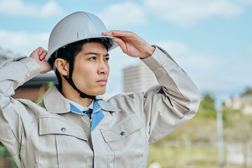 ヘルメットをかぶる作業服姿の男性