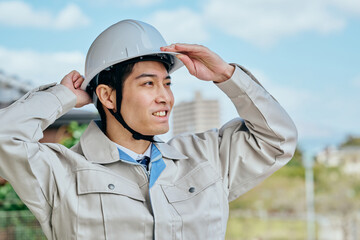 ヘルメットをかぶる作業服姿の男性